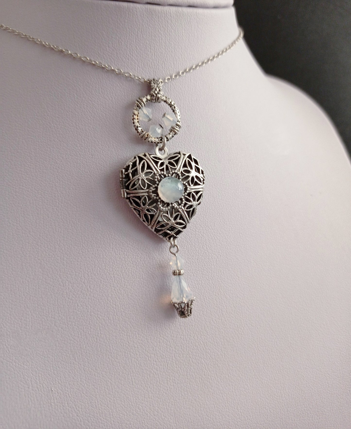 Silver heart locket necklace with a moonstone cabochon and white crystals.