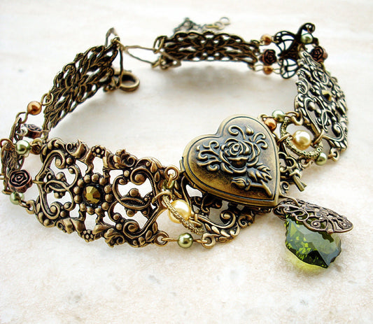 Ornate antique bronze filigree choker featuring a heart-shaped locket charm with a rose engraving and a dangling green faceted gemstone.