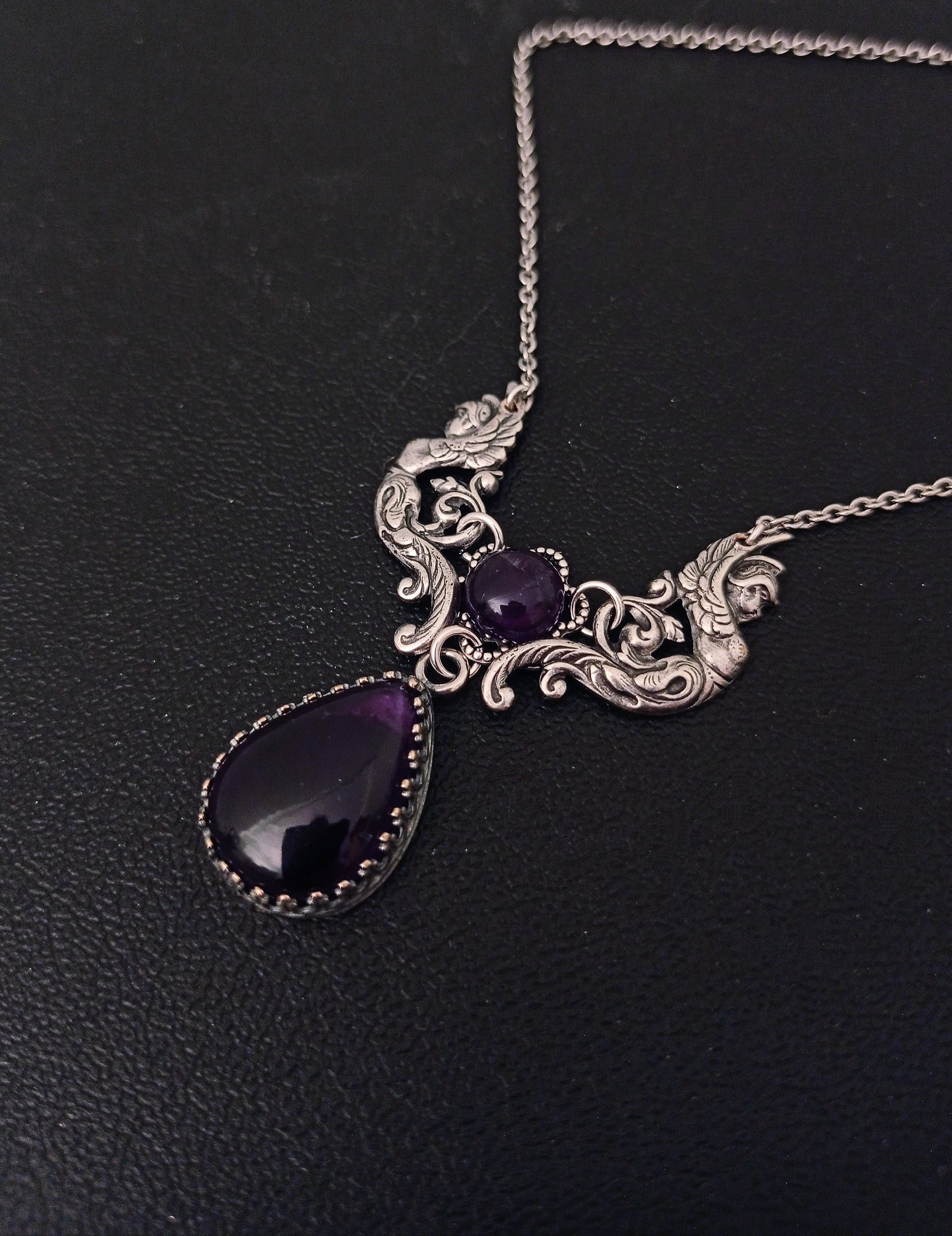 Victorian/Vintage Inspired necklace featuring a beautiful center piece with two winged angels in antique silver supporting two dark purple amethyst cabochons.