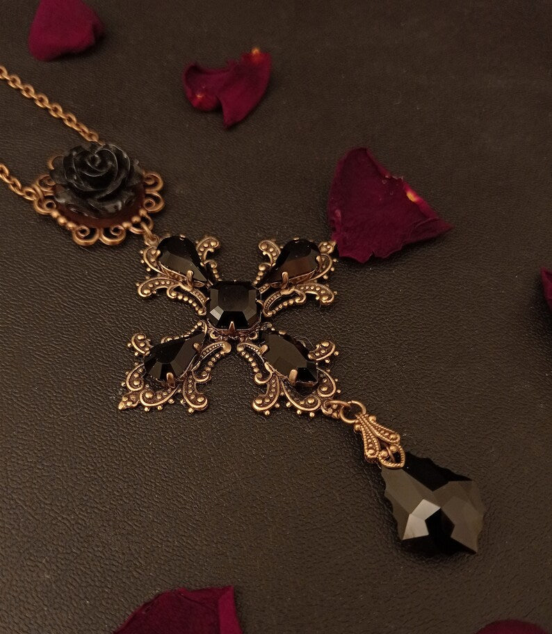 Decorative vintage style cross pendant inspired by Dolce and Gabbana with intricate design and black crystal jewels suspended from a chain by a black rose.