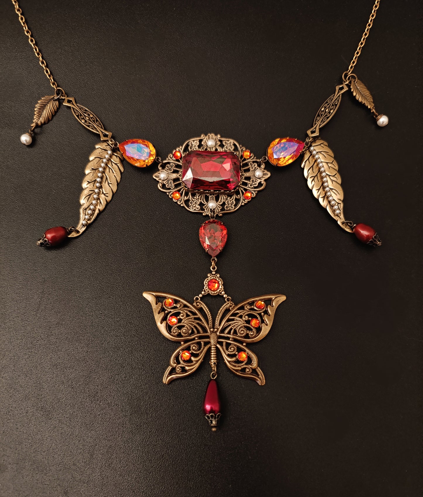 Fiery orange/red Austrian crystals come together with a large brass filigree butterfly and delicate white pearls in this necklace! 