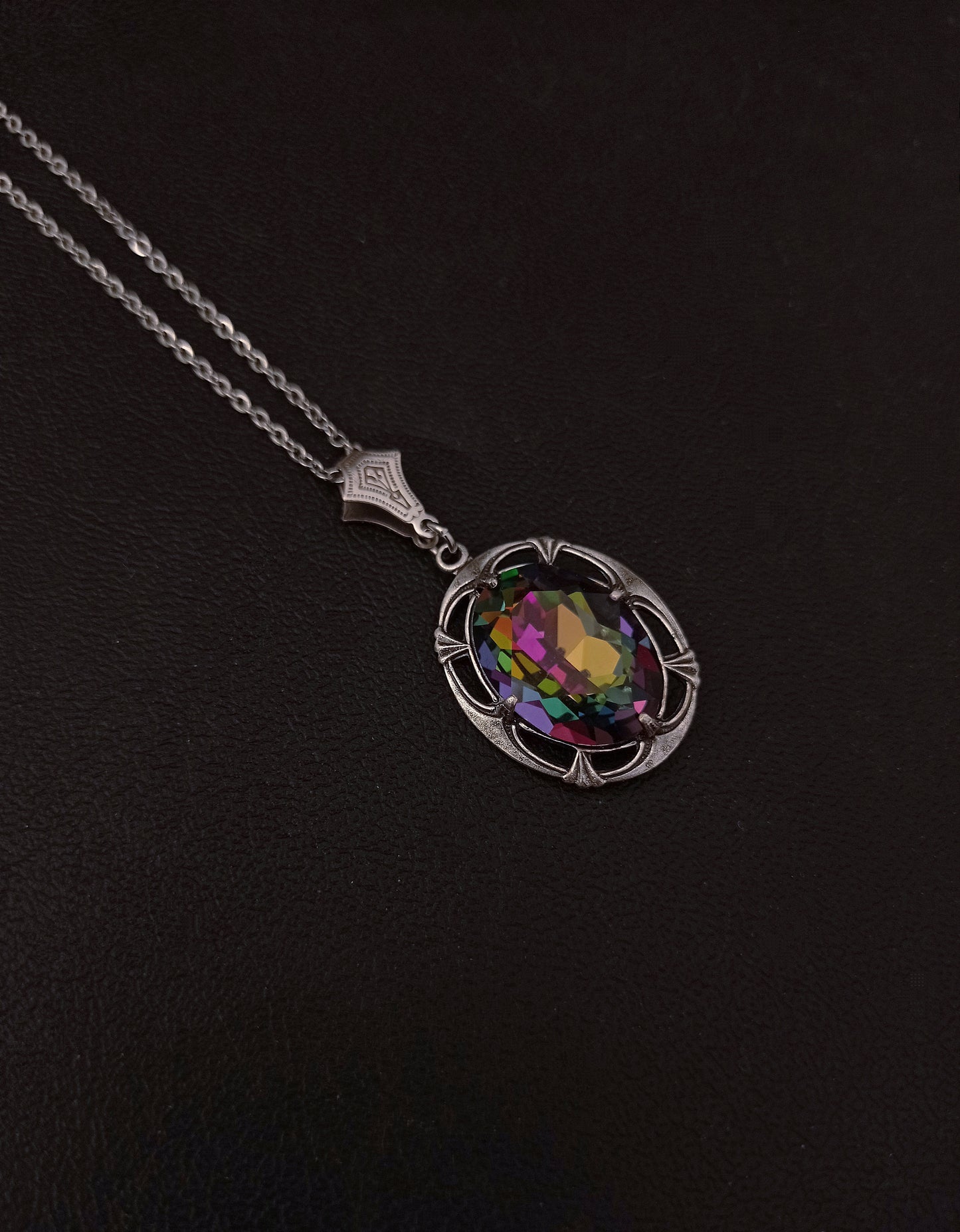 A multi-colored crystal necklace with an oval pendant set in an ornate silver mounting, suspended from a silver chain.