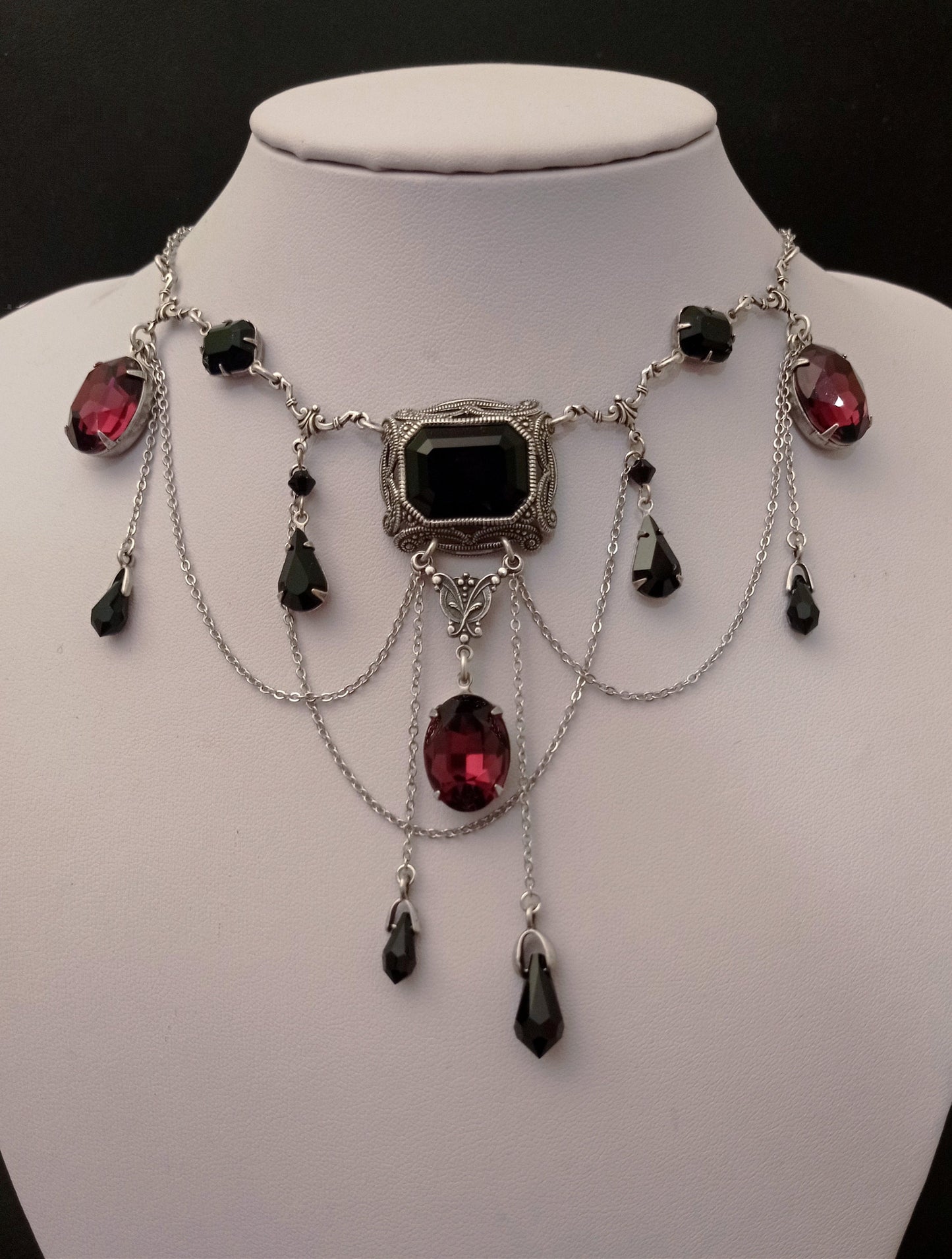 Victorian-style gothic necklace with black and burgundy Swarovski crystals and silver chains on display bust. Perfect for gothic wedding or cosplay. Gothic jewelry for women.