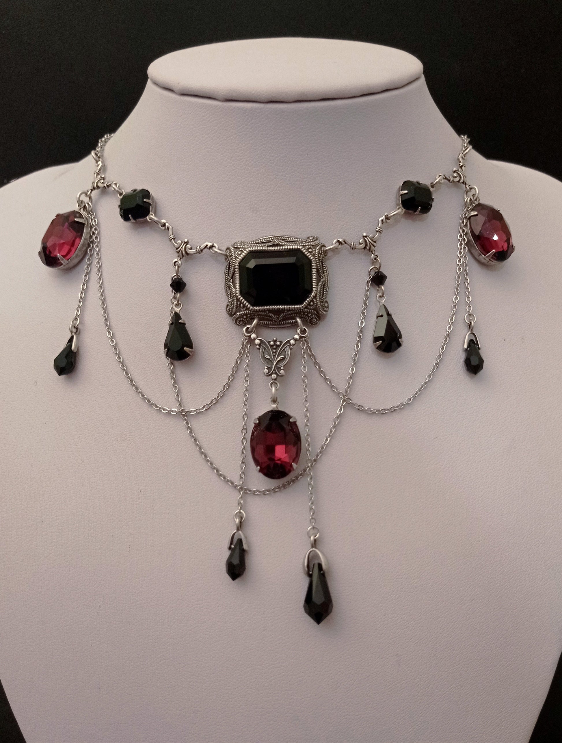 Victorian-style gothic necklace with black and burgundy Swarovski crystals and silver chains on display bust. Perfect for gothic wedding or cosplay. Gothic jewelry for women.