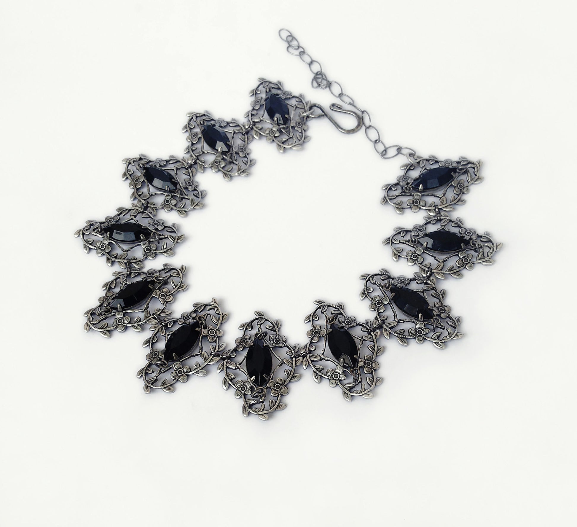 Exquisite silver jewelry artistry with delicate flower and leaves frames that showcase marquis shaped black crystals, radiating elegance and timeless allure.