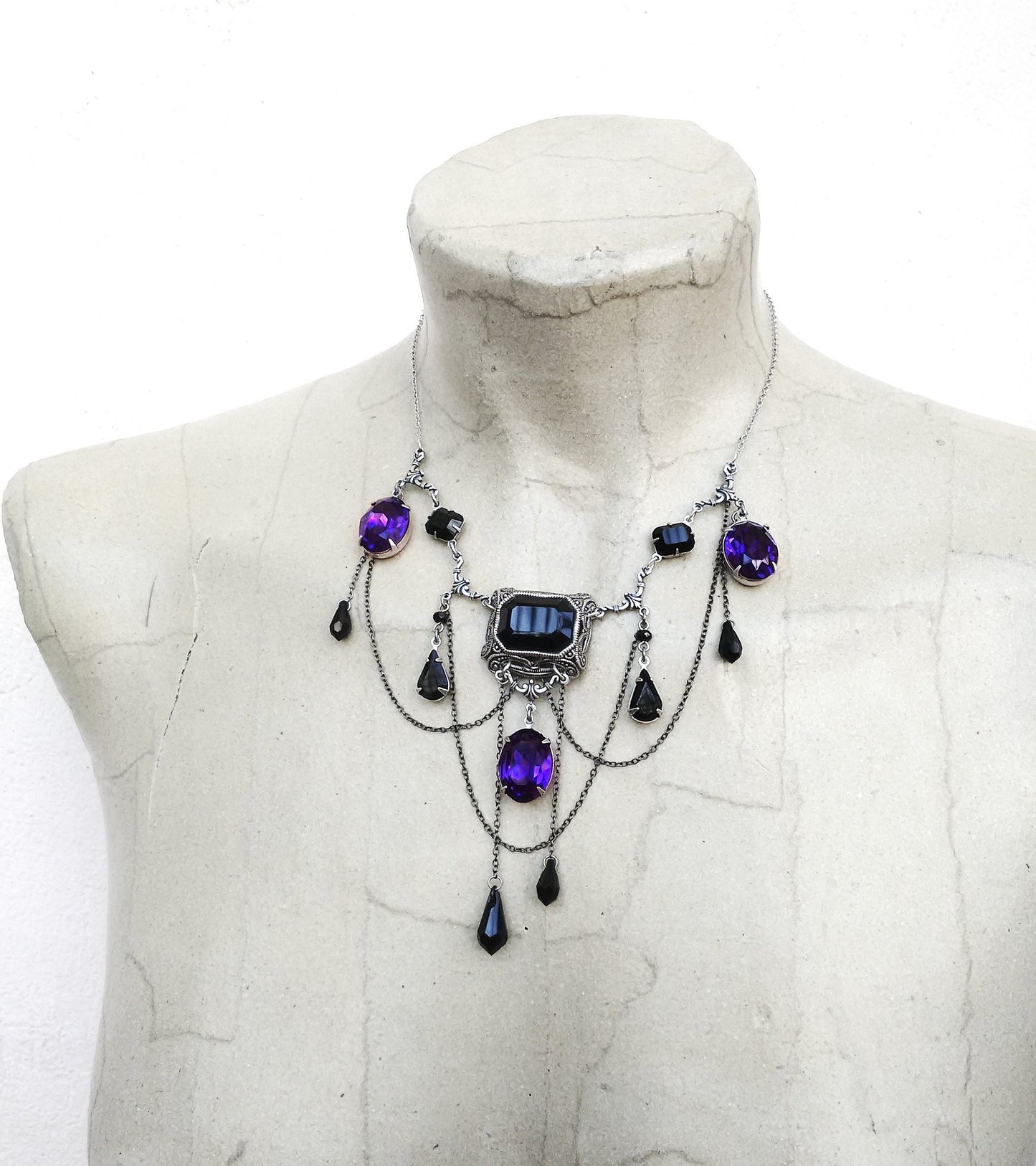 This statement gothic bib necklace has beautiful Black and Dark Purple crystals with oxidised silver filigree components and draping chains. Gothic Jewelry by Aranwen.
