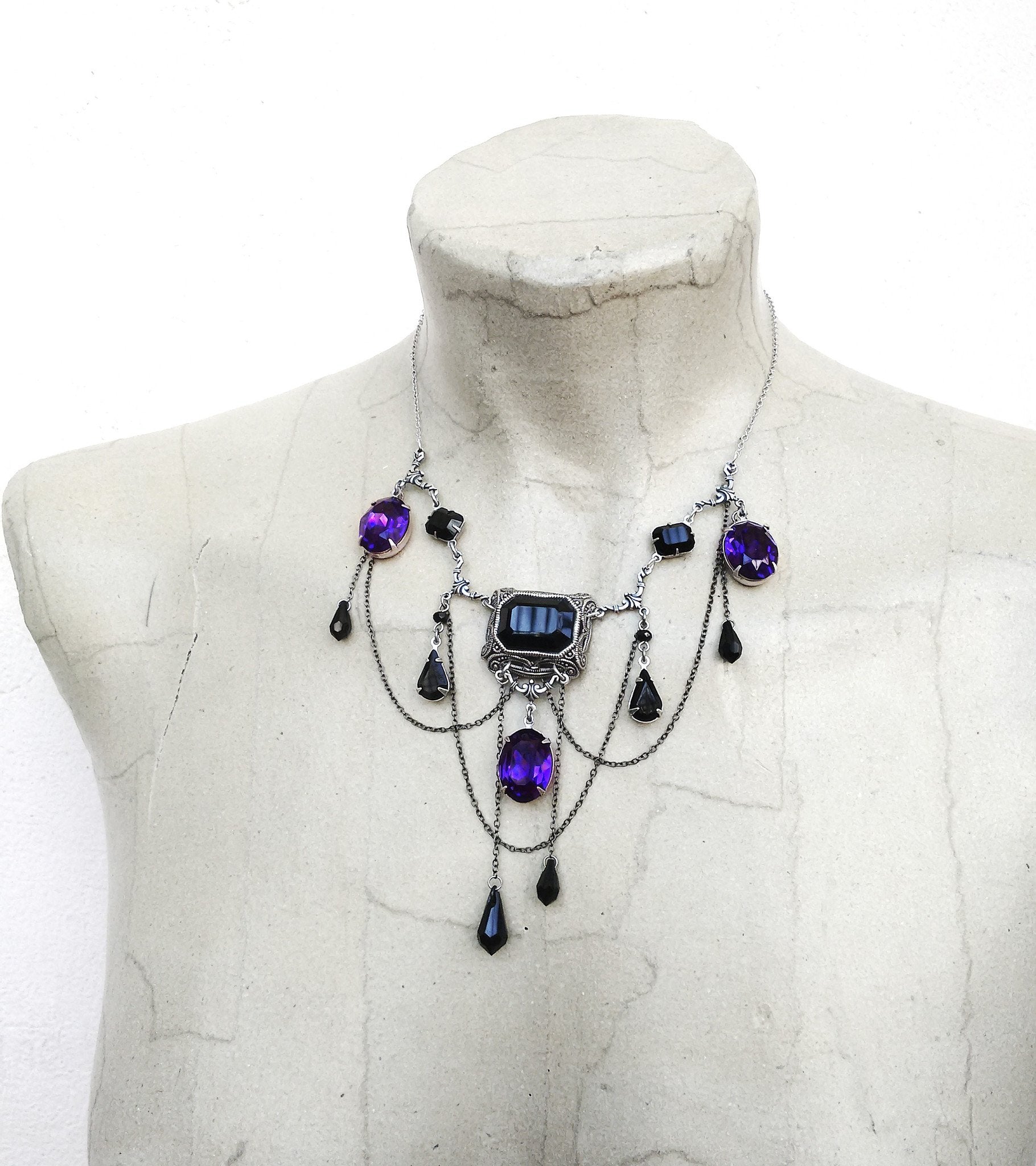 This statement gothic bib necklace has beautiful Black and Dark Purple crystals with oxidised silver filigree components and draping chains. Gothic Jewelry by Aranwen.